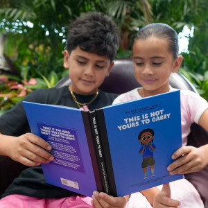 Two young children reading the book 'This is not yours to carry'